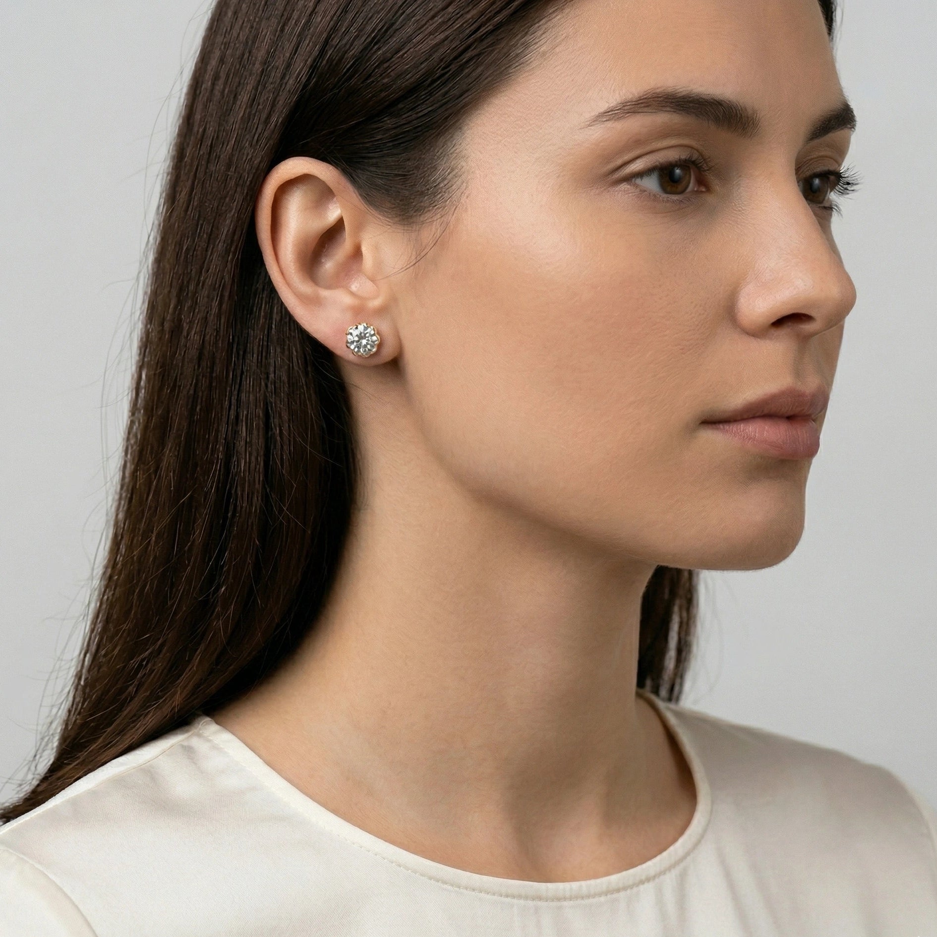 Woman wearing1 carat Blossom Moissanite flower stud earrings in 18K gold plated 925 sterling silver, side profile showing D color VVS1 stone and open blossom basket setting - Sensitive Stones