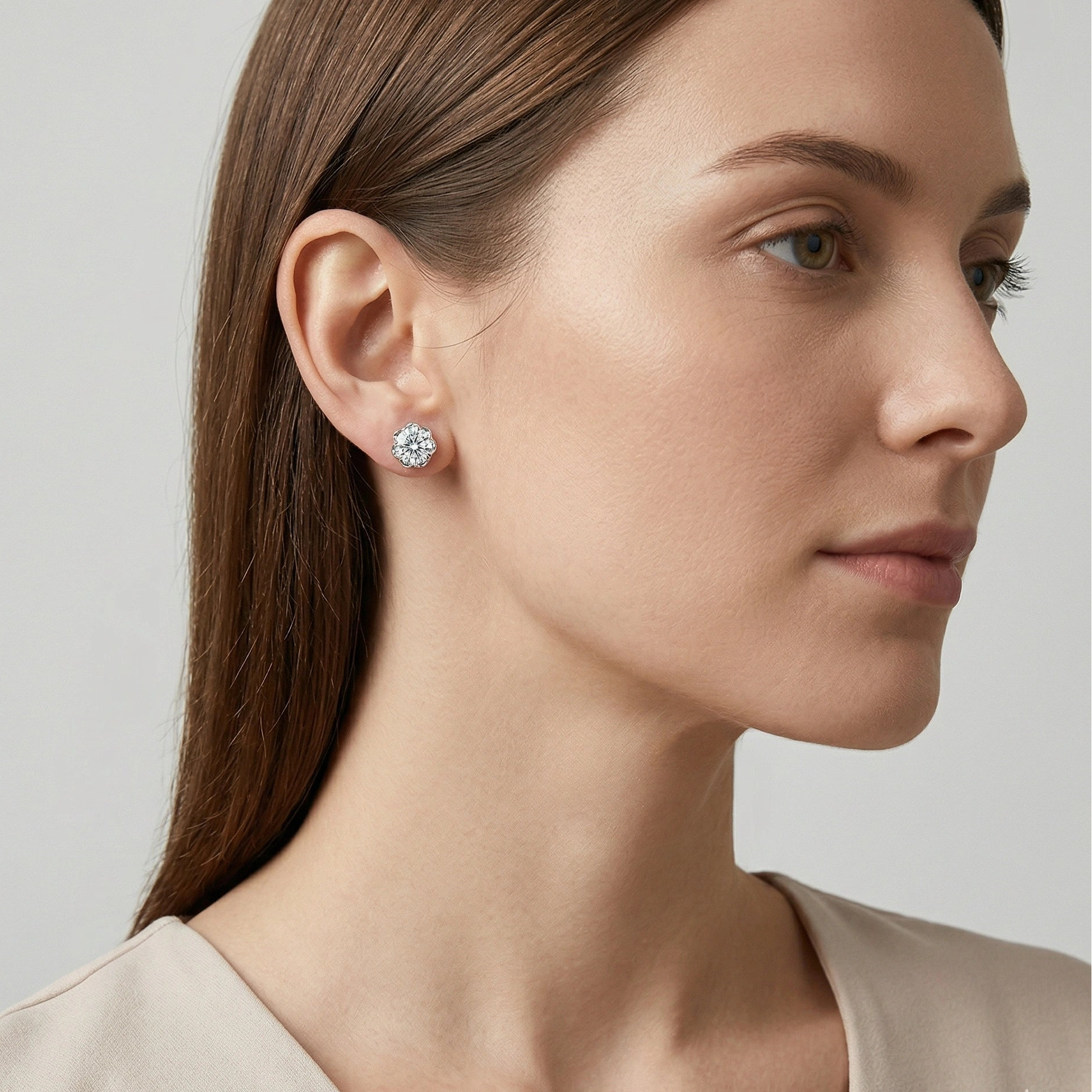 Caucasian woman in neutral blouse wearing Blossom Moissanite flower stud earrings in silver, side profile showing realistic on-ear size, D color VVS1 stone and soft floral basket setting - Sensitive Stones