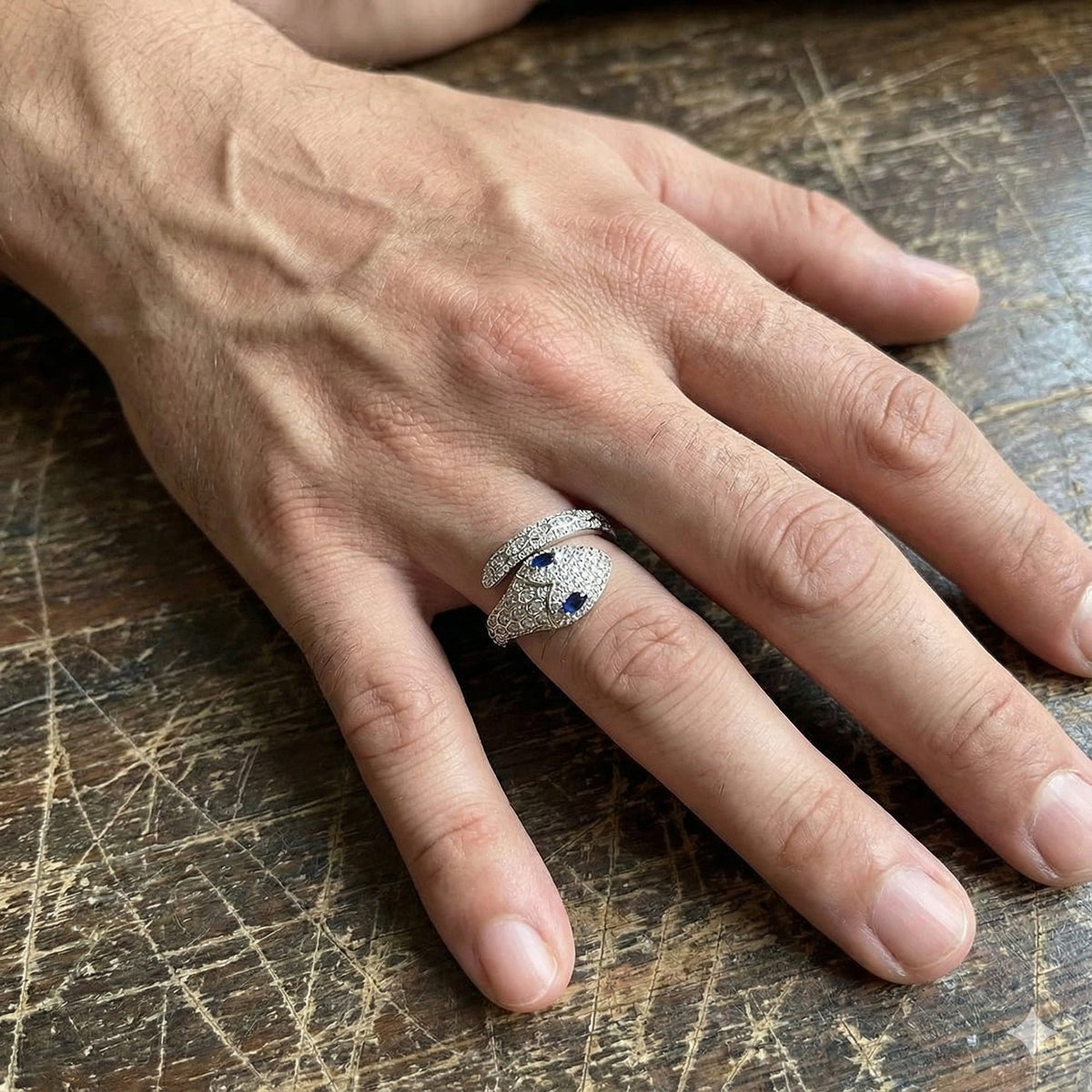 Man's hand wearing the blue-eyed moissanite snake ring in 925 sterling silver with a white gold finish - Sensitive Stones