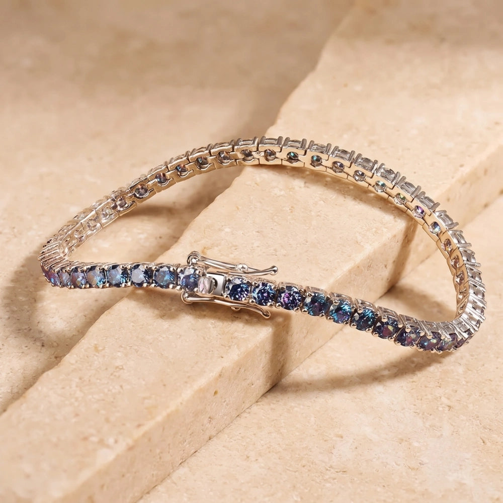 Blue moissanite tennis bracelet set in 925 sterling silver laid on warm beige surface, reflective vivid blue sparkle – Sensitive Stones