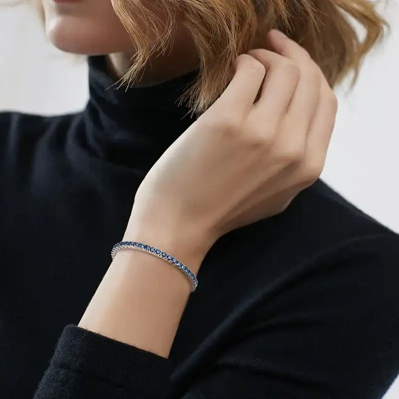 Model wearing blue moissanite tennis bracelet styled with black long-sleeve outfit, quiet luxury jewelry look – Sensitive Stones