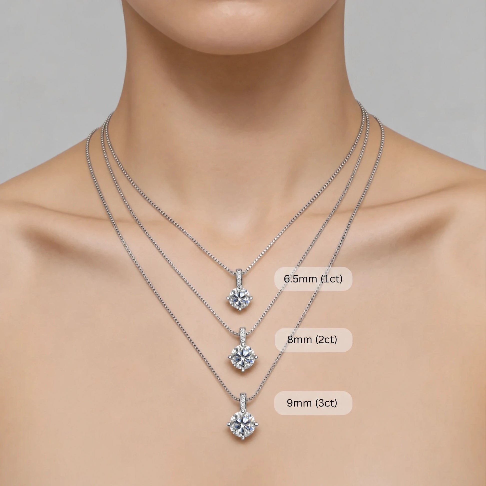 Woman wearing three layered Celeste moissanite solitaire necklaces in sterling silver showing size comparison: 6.5mm 1ct, 8mm 2ct, and 9mm 3ct pendant options