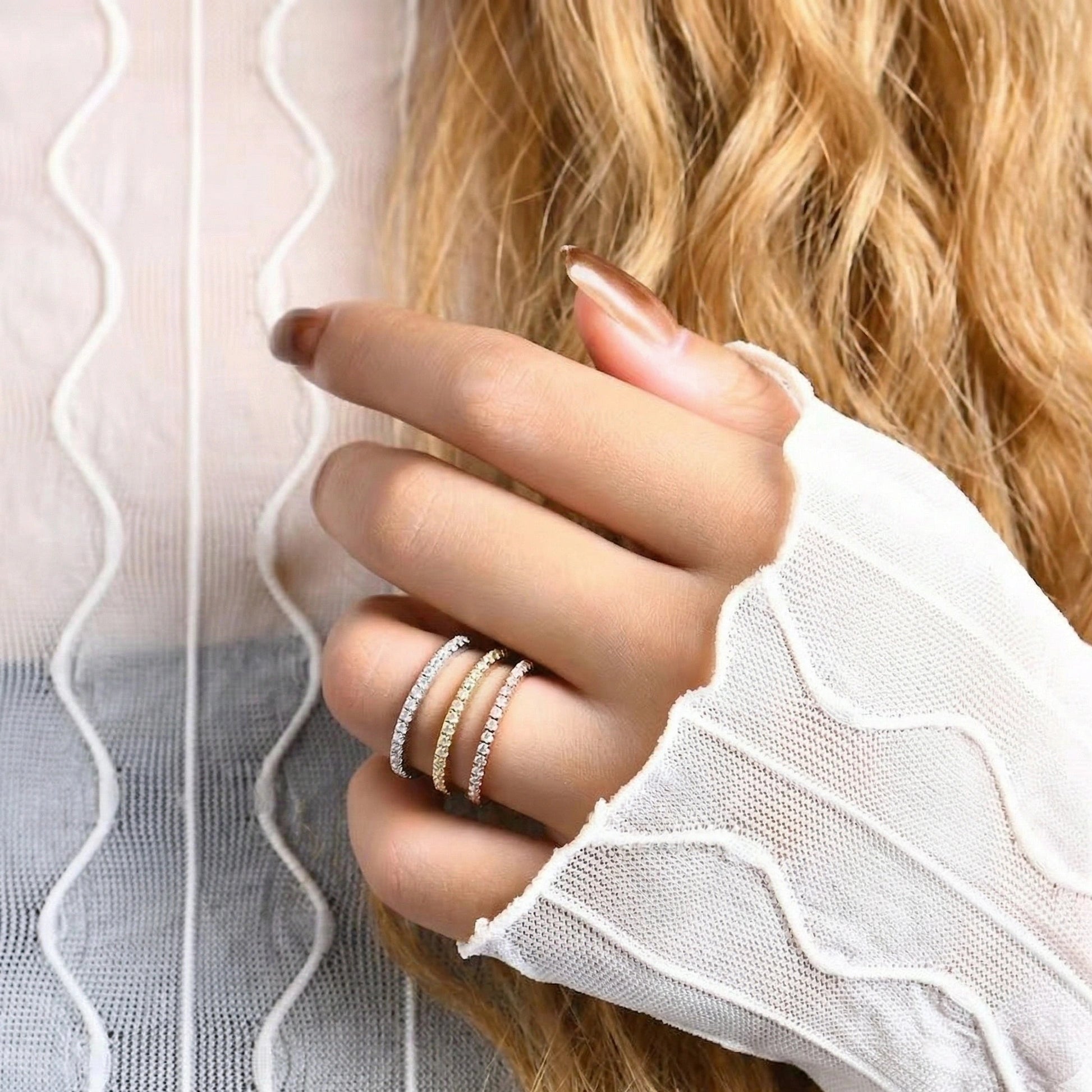 Close-up of a woman's hand wearing silver moissanite ring in white gold, yellow gold and rose gold finish on same finger - Sensitive Stones