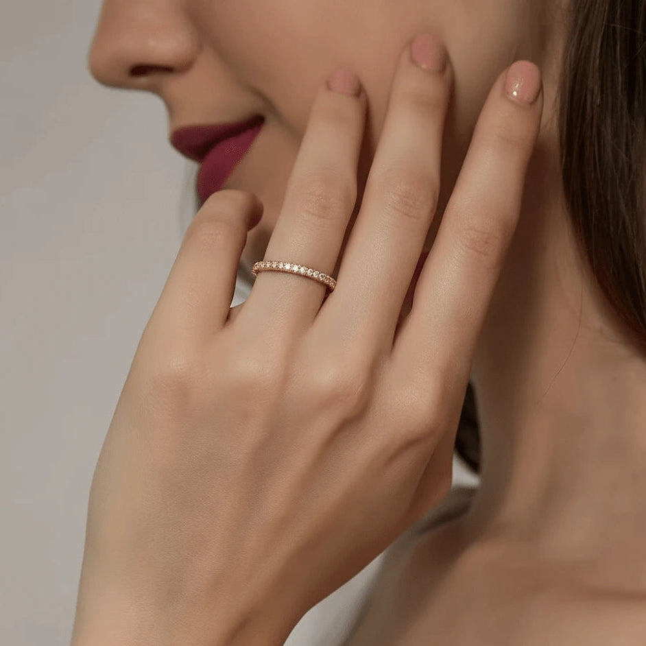 Close-up of a woman's hand wearing a yellow gold plated silver moissanite ring with a neutral background - Sensitive Stones