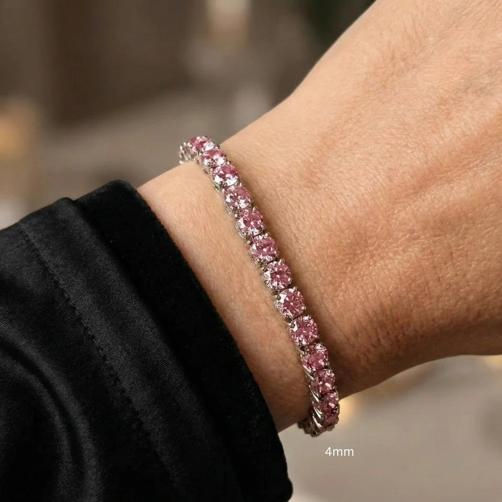 Close up of a wrist wearing 4mm pink moissanite tennis bracelet with round-cut stones in white gold plated sterling silver, worn with white outfit - Sensitive Stones