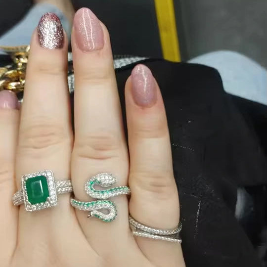 Hand wearing multiple rings featuring Coile Moissanite Snake Ring in 925 Silver and other rings