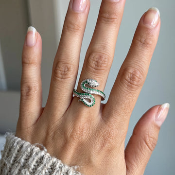 Woman's hand wearing the coiled moissanite snake ring in a white gold finish with green lab-created emeralds along the serpent body - Sensitive Stones