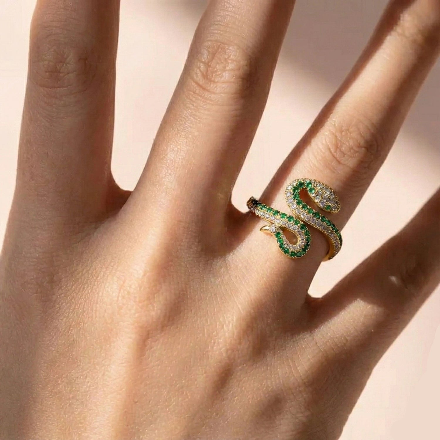 Woman wearing gold plated coiled moissanite snake ring with green gemstones - Sensitive Stones