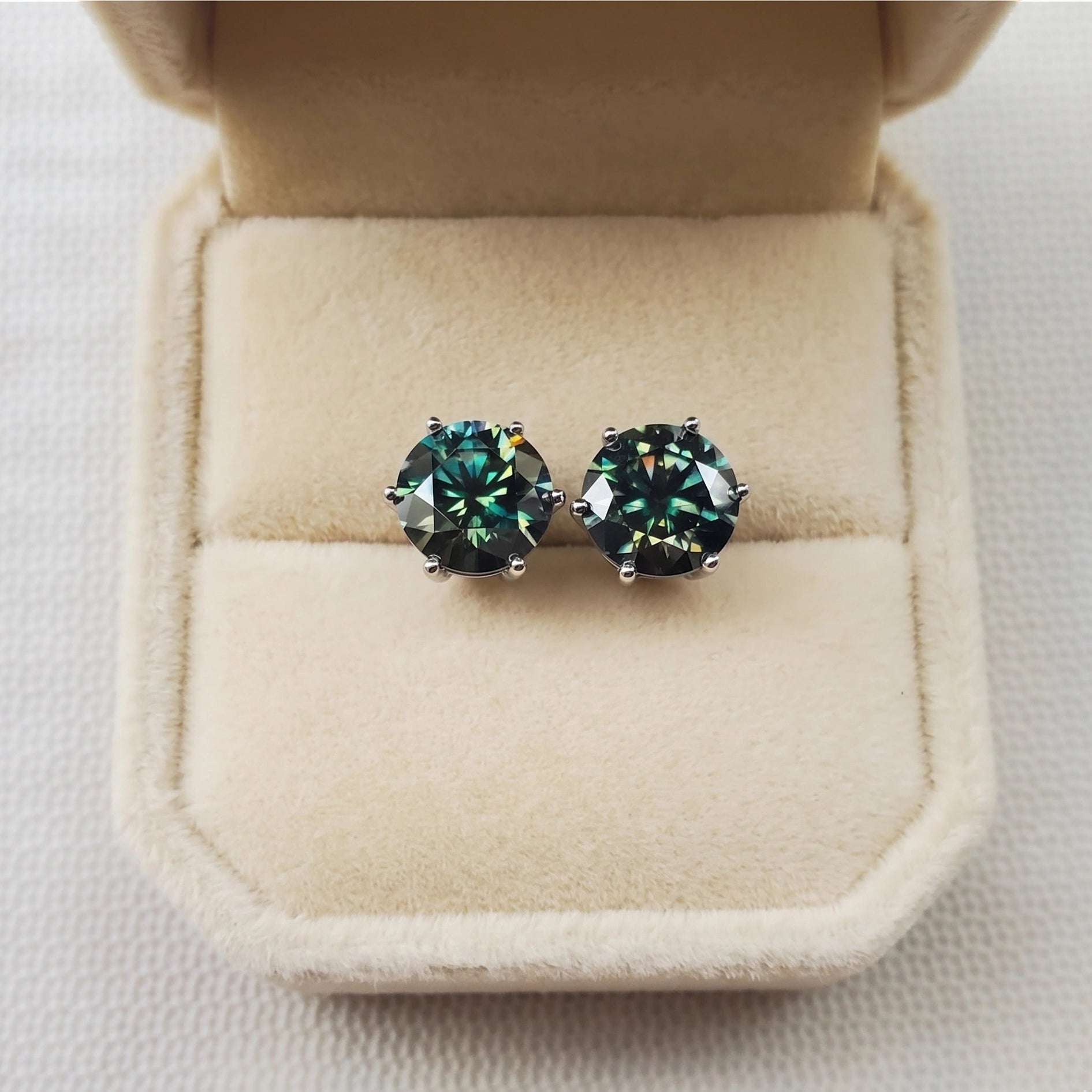 Dark green moissanite solitaire stud earrings in 6 prong setting, front view in open cream jewelry box - Sensitive Stones