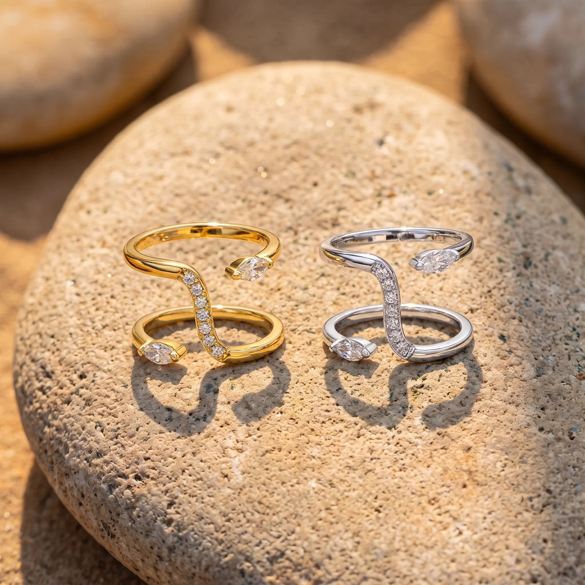 Double snake moissanite rings in yellow gold and white gold finishes side by side on a stone - Sensitive Stones