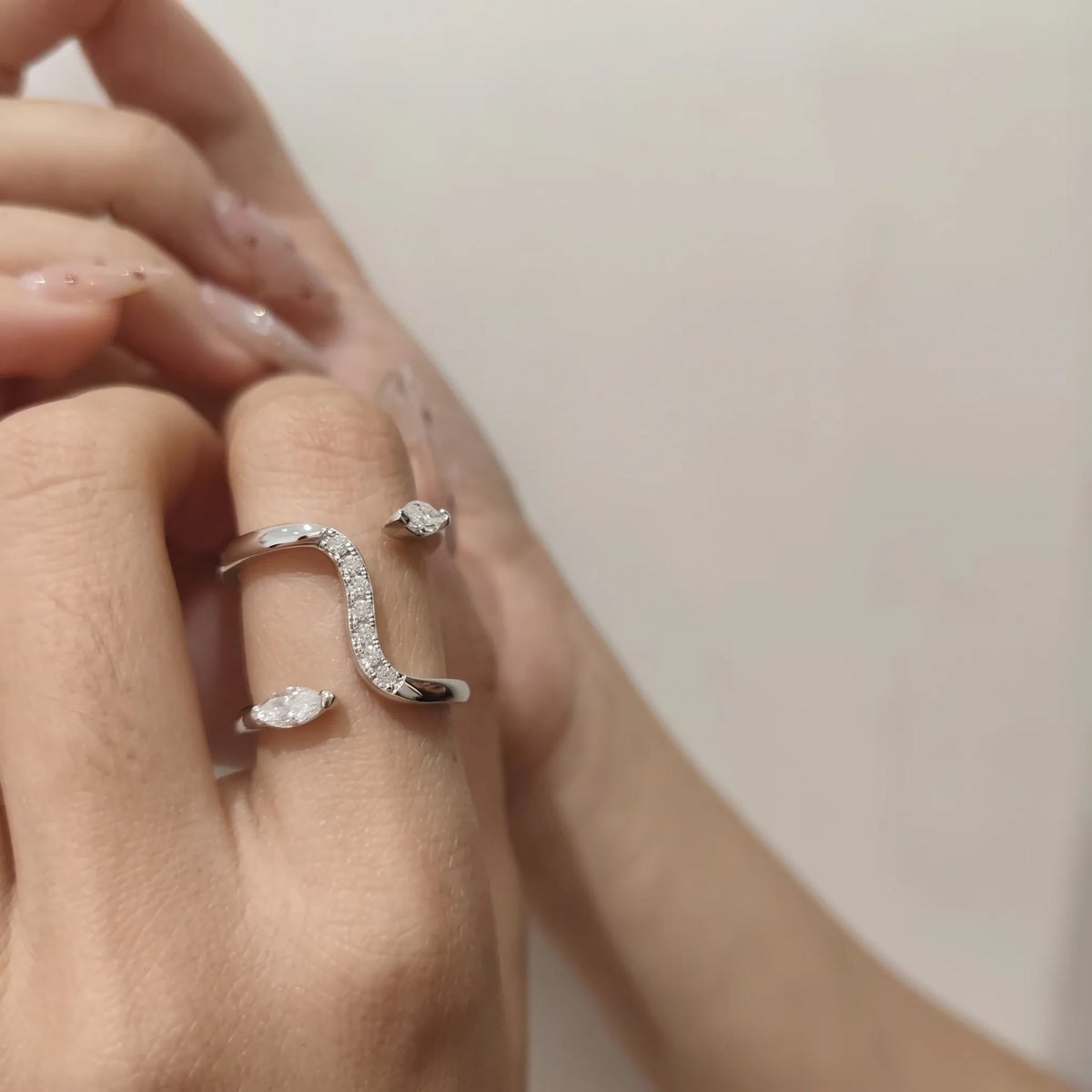 Double snake moissanite ring in a white gold finish worn on a woman's finger - Sensitive Stones