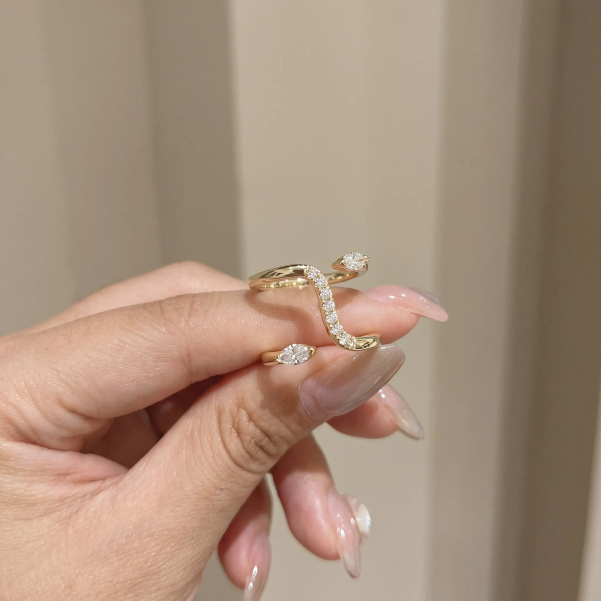 Woman holding the double snake moissanite ring in a yellow gold finish, showing the marquise moissanite heads and pavé body - Sensitive Stones