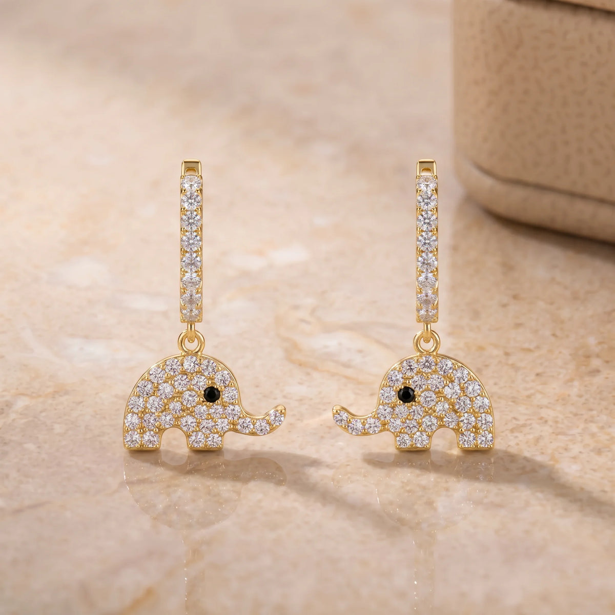 Pair of elephant dangle moissanite earrings in 14K gold filled shown on a stone surface - Sensitive Stones
