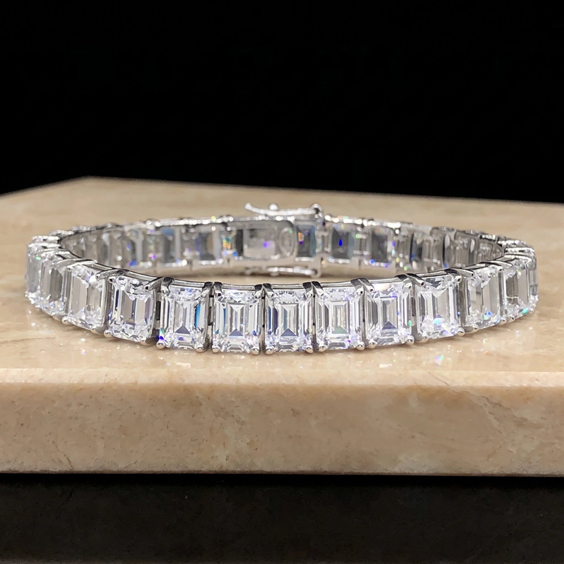Emerald cut moissanite tennis bracelet on a stone surface, east-west set step-cut stones and box clasp in 925 sterling silver - Sensitive Stones