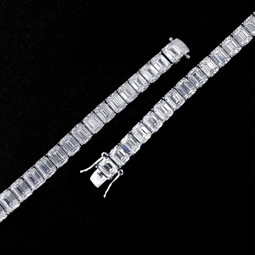 Emerald cut moissanite tennis bracelet laid flat on a black background, showing the full line of step-cut stones and box clasp - Sensitive Stones