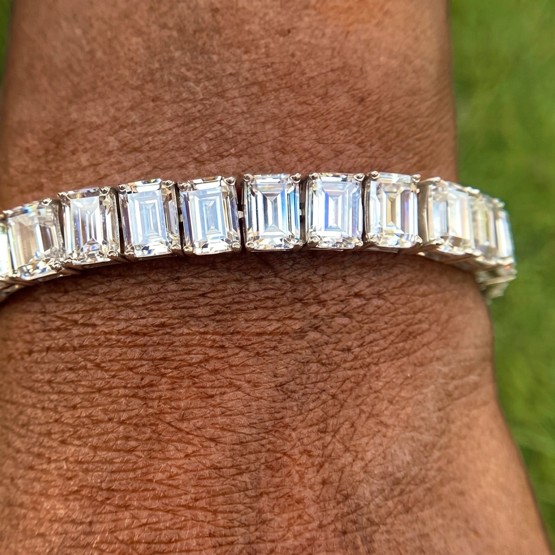Close-up of an emerald cut moissanite tennis bracelet worn on the wrist, showing the step-cut facets in 925 sterling silver - Sensitive Stones