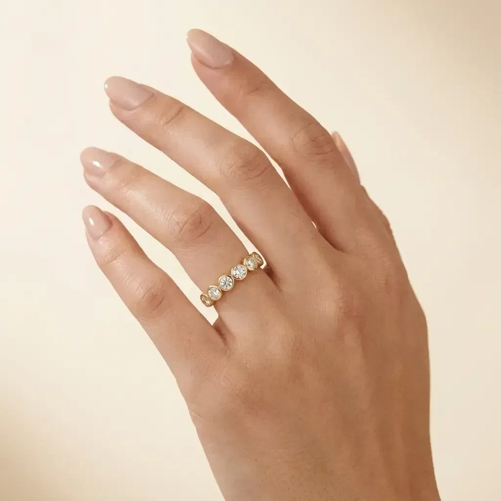 Woman wearing the five stone bezel moissanite ring in yellow gold on her ring finger - Sensitive Stones