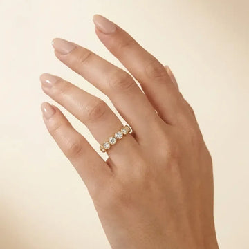 Woman wearing the five stone bezel moissanite ring in yellow gold on her ring finger - Sensitive Stones