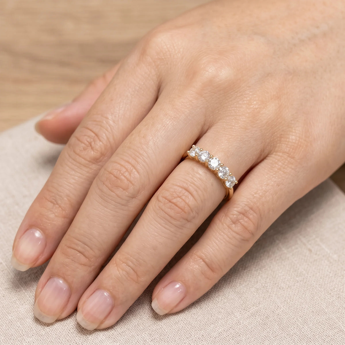 Five stone moissanite stackable ring in 14K gold filled worn on a hand, five 3.5mm stones in a close row across the finger - Sensitive Stones