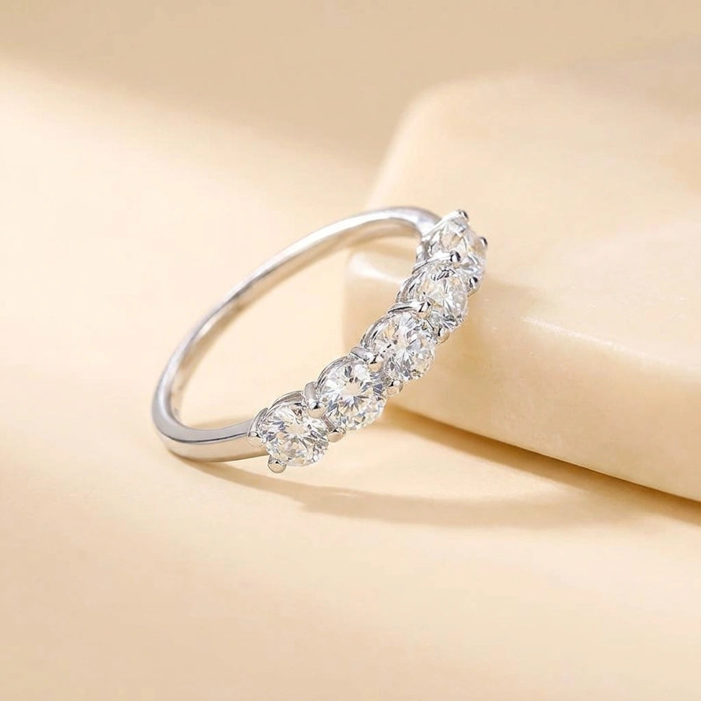 Five stone moissanite wedding band in 925 sterling silver white gold resting on a cream stone ledge - Sensitive Stones