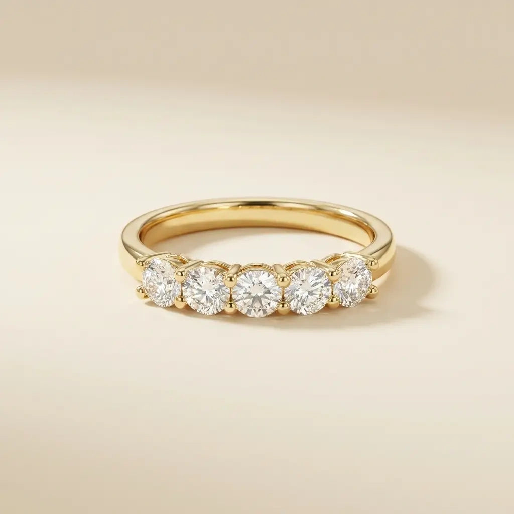 Five stone moissanite wedding band in yellow gold on a warm cream surface - Sensitive Stones