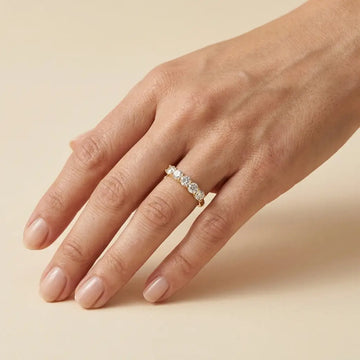 Woman wearing the five stone moissanite wedding band in yellow gold on her ring finger - Sensitive Stones