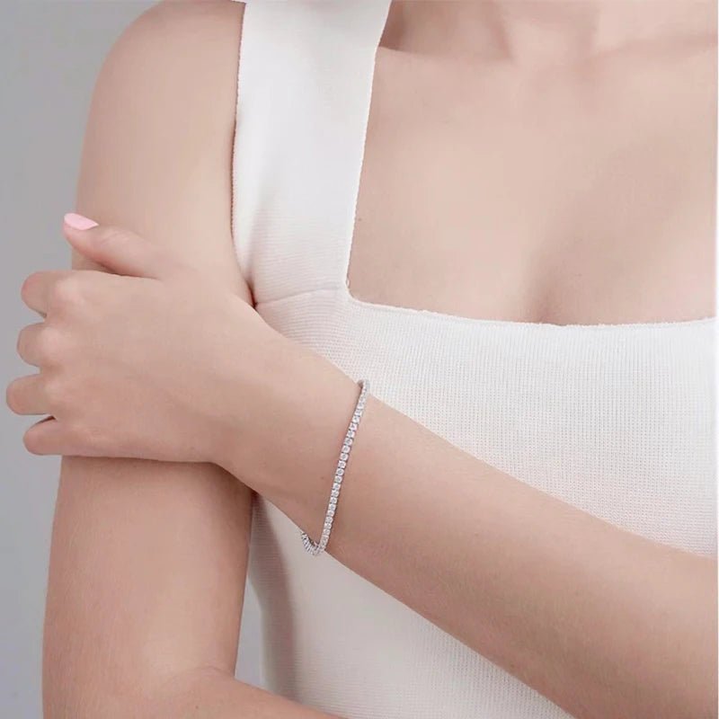 Women's moissanite tennis bracelet in white gold plating, worn with soft natural lighting.