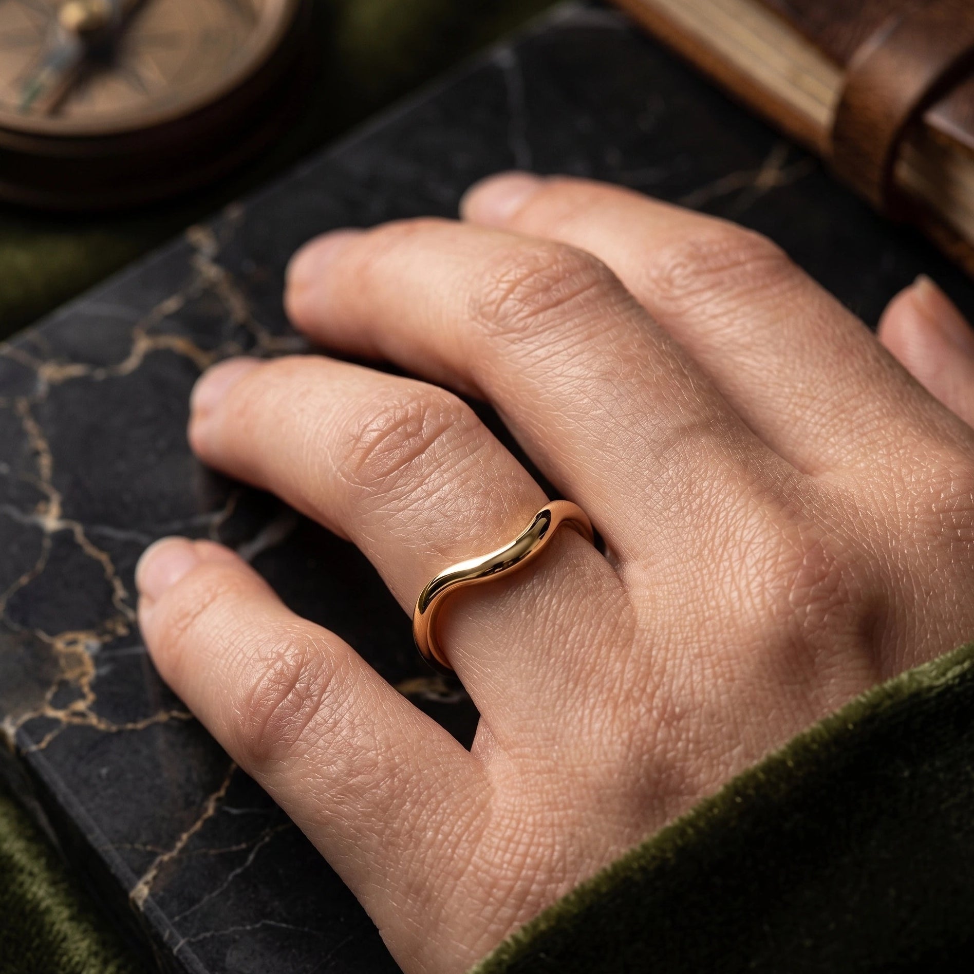 Gold filled asymmetric wave stacking ring worn on hand against dark leather journal lifestyle shot - Sensitive Stones