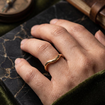 Gold filled asymmetric wave stacking ring worn on hand against dark leather journal lifestyle shot - Sensitive Stones