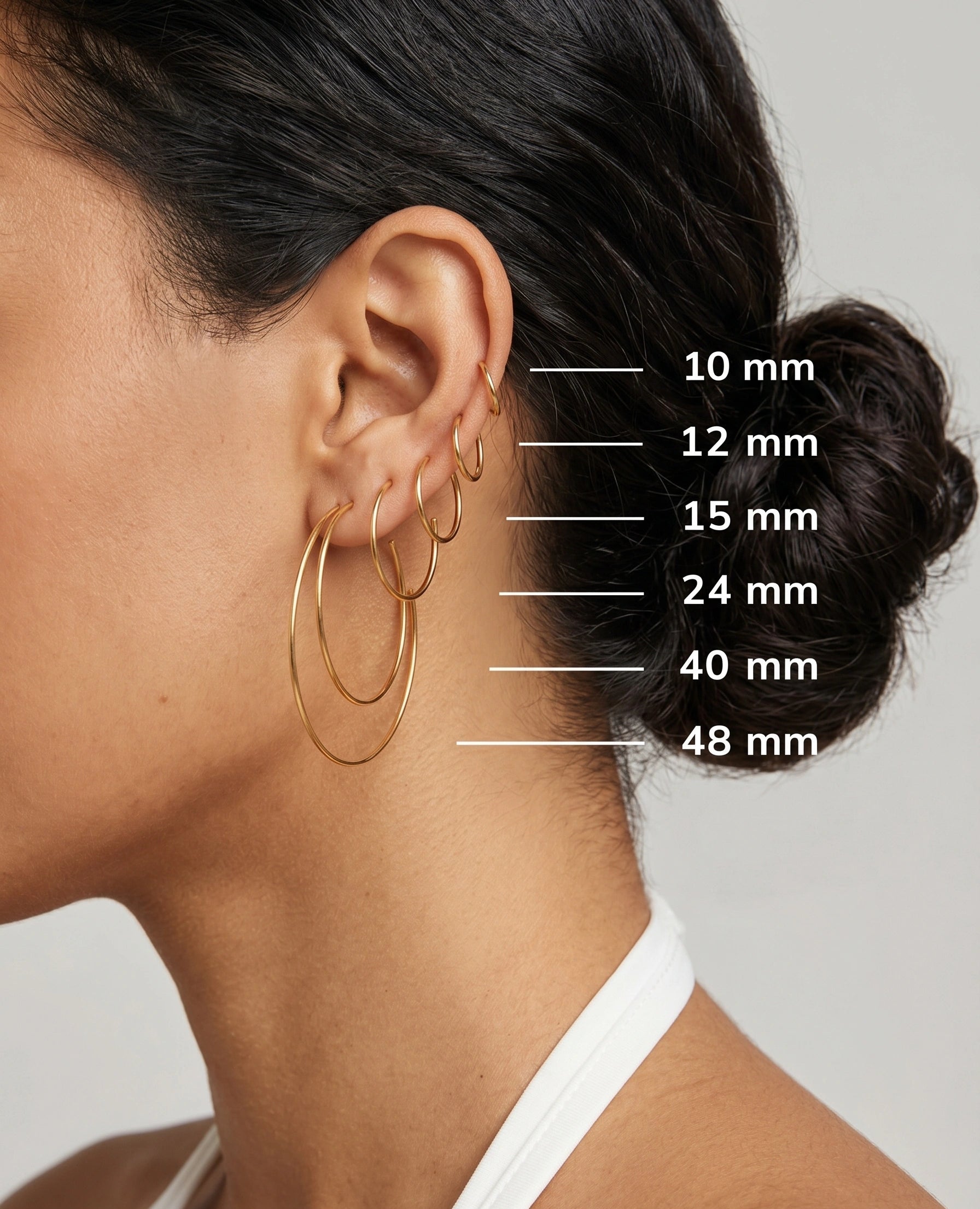 Side view of a woman wearing multiple thin gold hoop earrings in one ear, showing a size guide with labeled diameters 10 mm, 12 mm, 15 mm, 24 mm, 40 mm, and 48 mm.