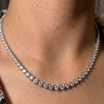 Close-up of a graduated moissanite tennis necklace worn on the neck, showing the three-prong settings and the fire in the stones