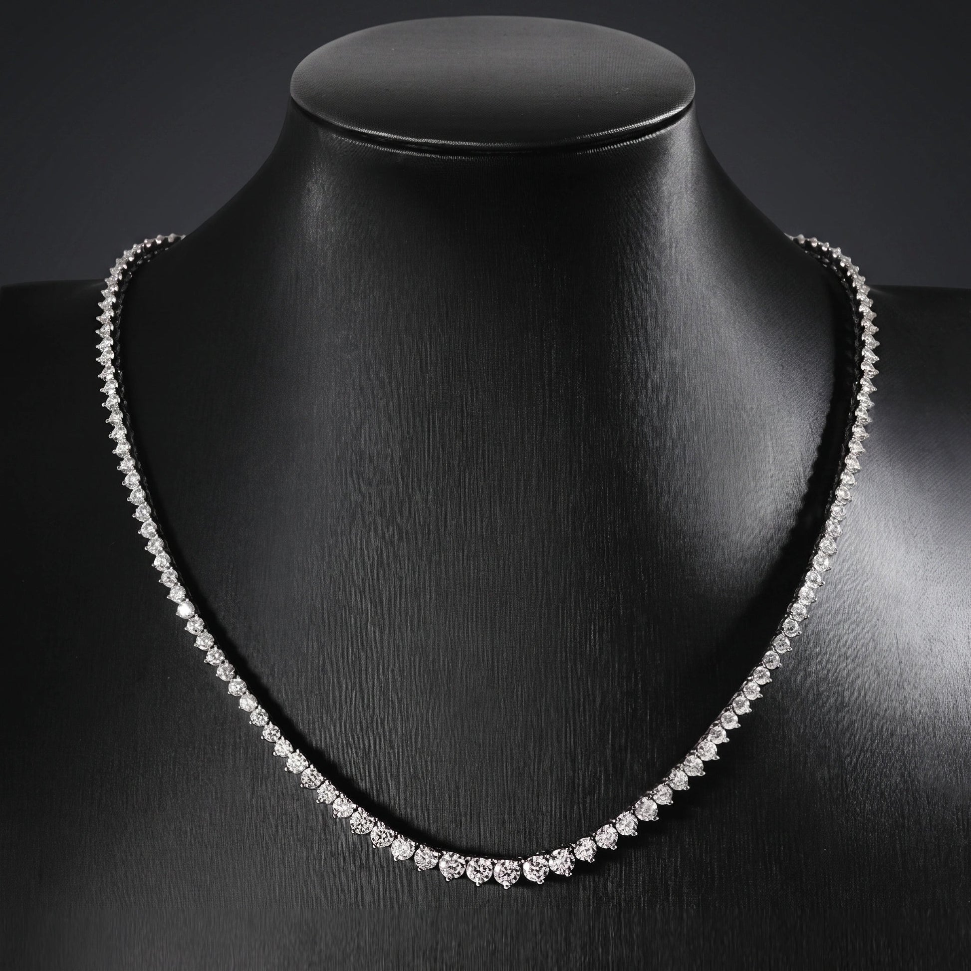 Graduated moissanite tennis necklace on a black display bust, showing the riviera taper toward the centre front