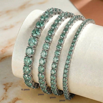Green moissanite tennis bracelet in 925 sterling silver showing four stone sizes 3mm 4mm 5mm and 6.5mm on marble display - Sensitive Stones