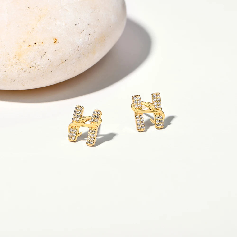 Gold 'H' shaped earrings on a light background
