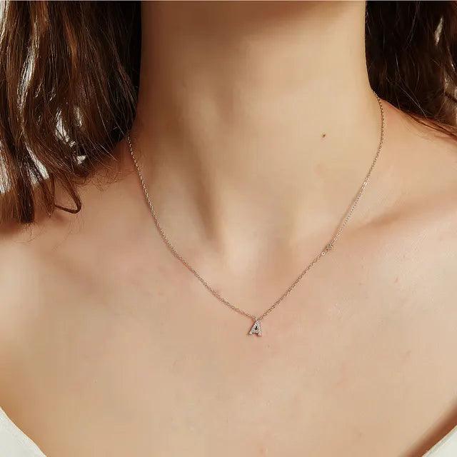 Sterling silver A initial necklace with zirconia charm worn with minimalist white top.