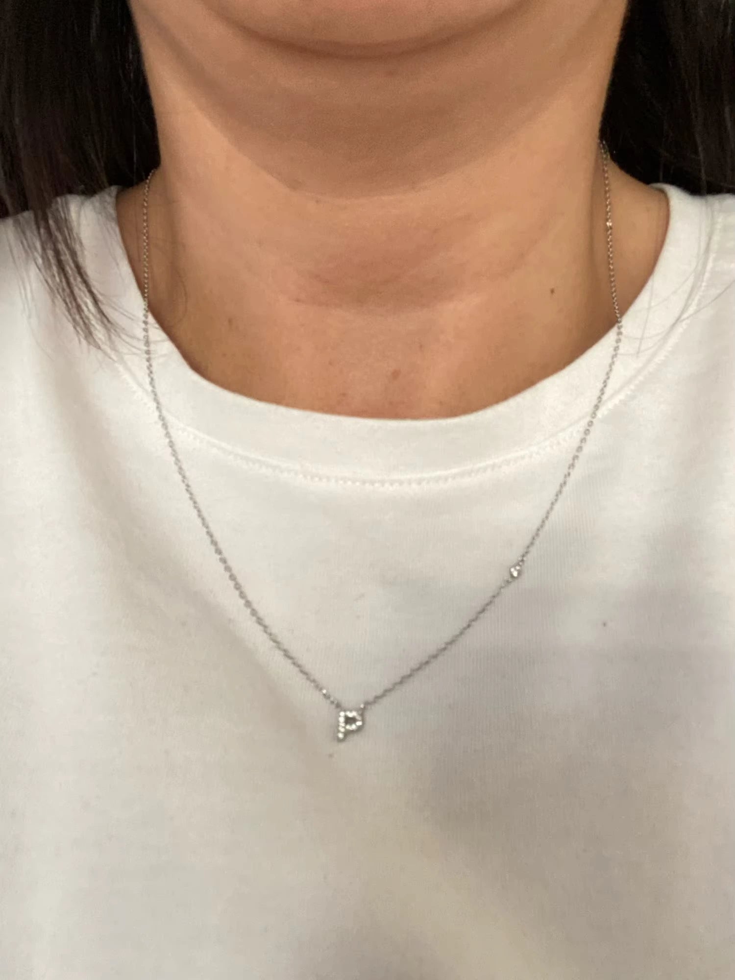 Sterling silver P initial necklace with zirconia charm styled casually over a white t-shirt.