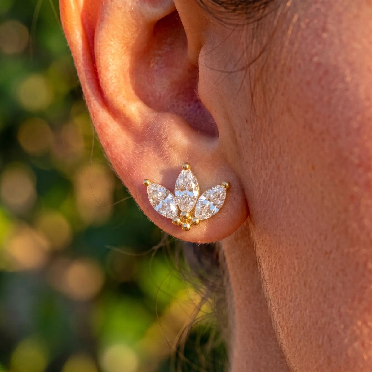 Close-up of a lotus marquise moissanite stud earring in 14K gold filled on the lobe in daylight - Sensitive Stones