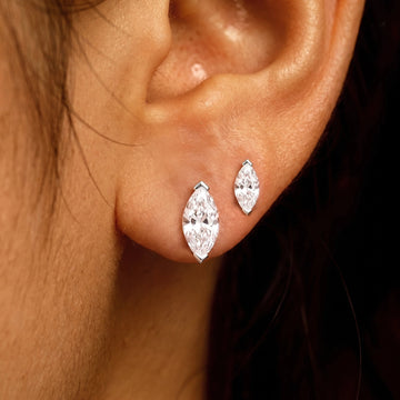 Two white gold marquise cut moissanite studs worn in stacked lobe piercings, a V-prong capping each point