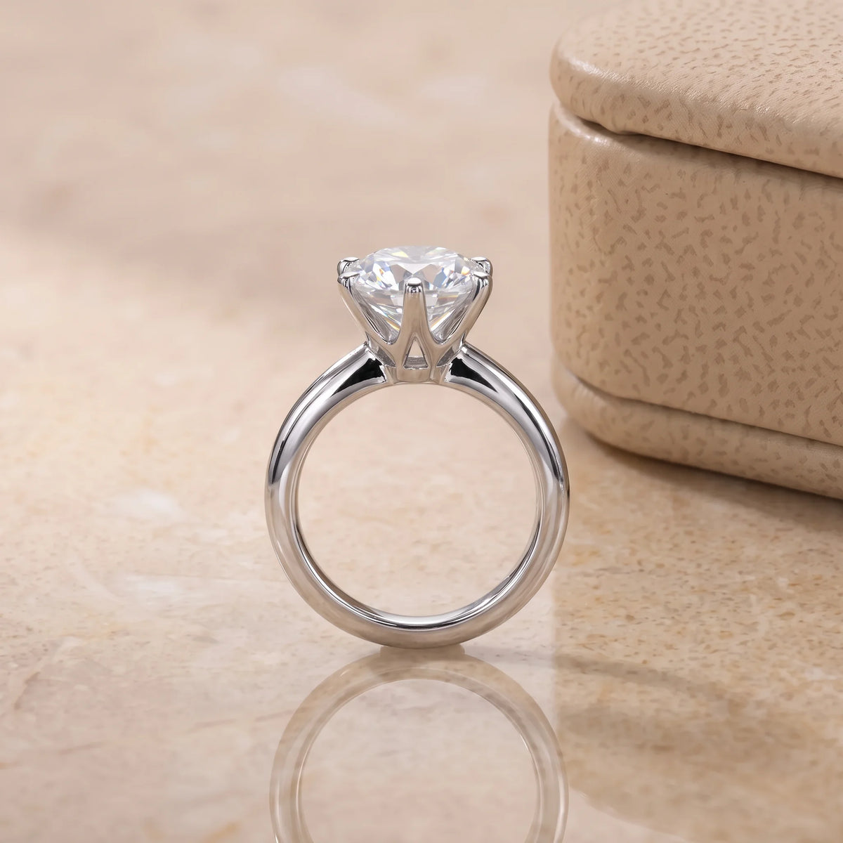 Classic moissanite solitaire ring side profile showing the open gallery under the 6-prong setting beside a cream ring box - Sensitive Stones