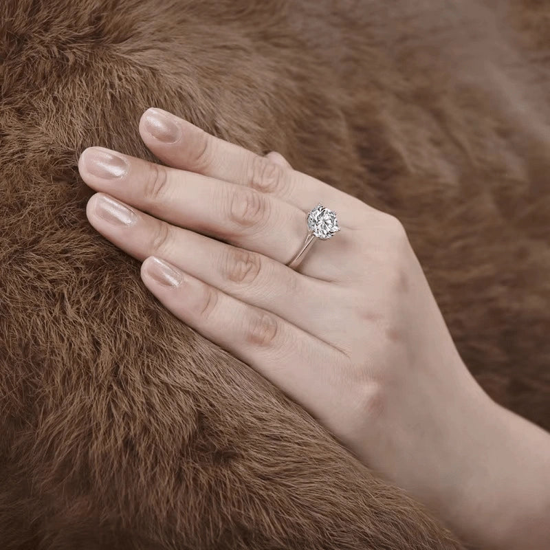 Hand wearing a classic moissanite solitaire ring in 925 silver on a brown fur background - Sensitive Stones