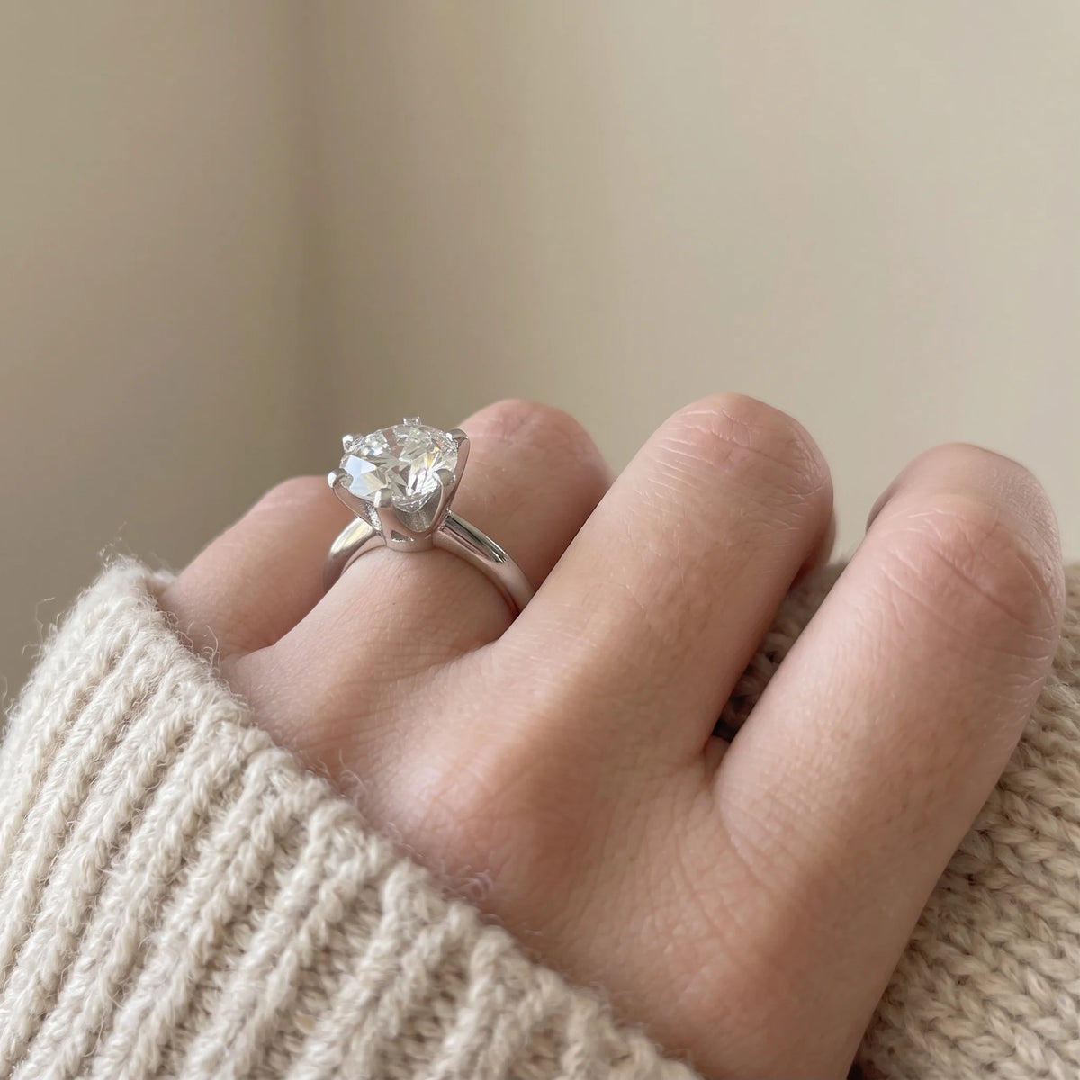 Classic moissanite solitaire ring worn on the hand against a cream knit sweater showing the 6-prong setting - Sensitive Stones