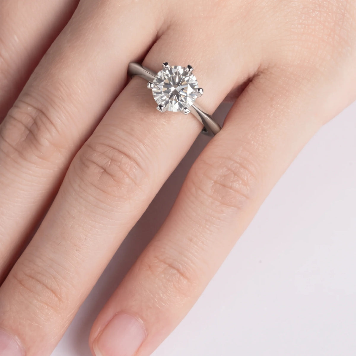 Hand wearing the classic moissanite solitaire ring in 925 sterling silver on a plain white background - Sensitive Stones