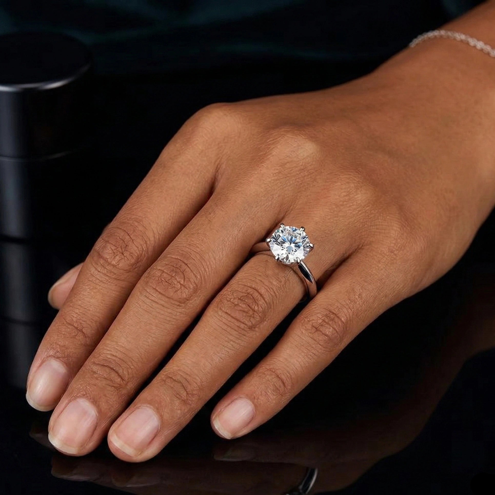 Classic moissanite solitaire ring 6-prong worn on hand dark background - Sensitive Stones