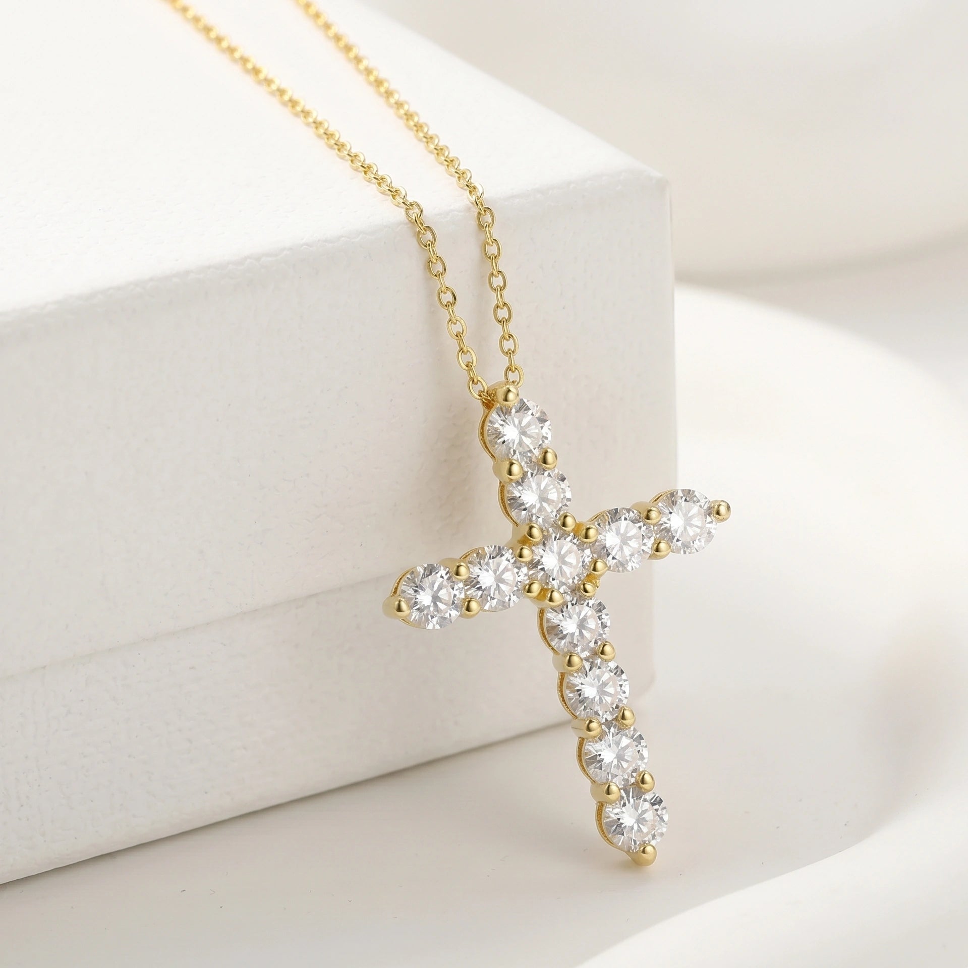 Moissanite cross necklace with D color VVS1 stones in 925 silver with 18k gold finish hanging against a white jewelry box - Sensitive Stones