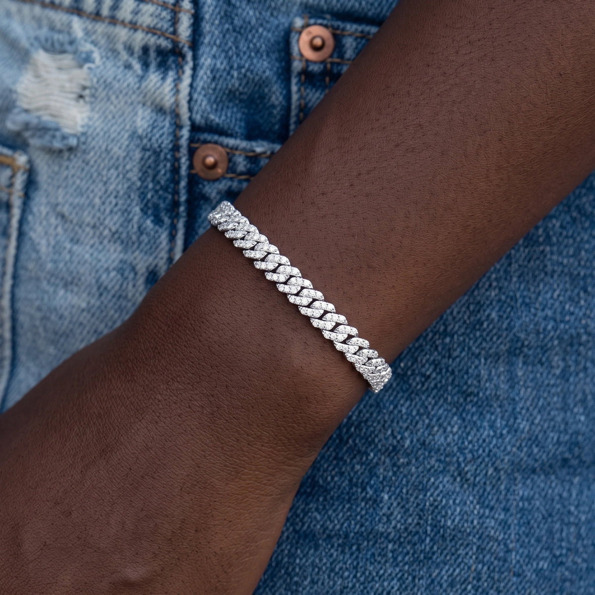 White gold 6mm moissanite Cuban link bracelet worn on the wrist with denim