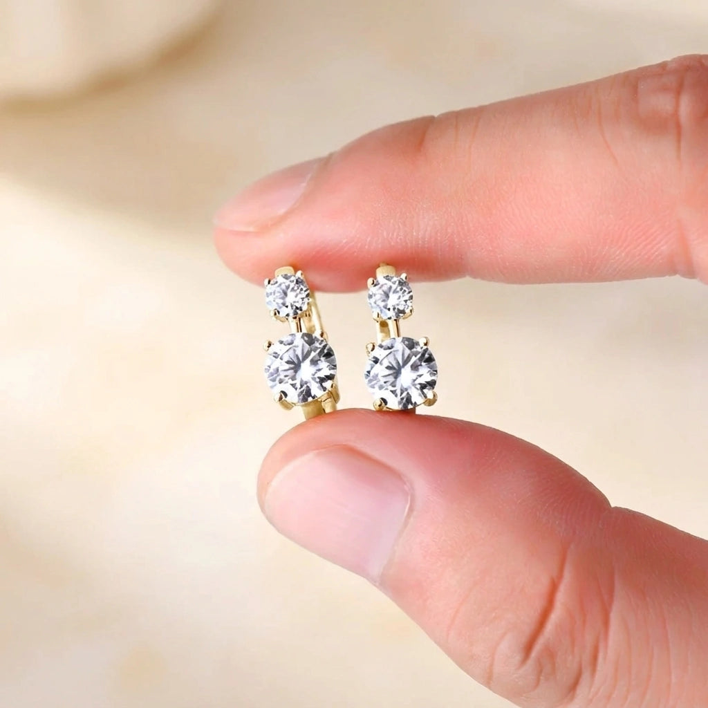 Two stone moissanite huggie hoop earrings in yellow gold held in hand - Sensitive Stones