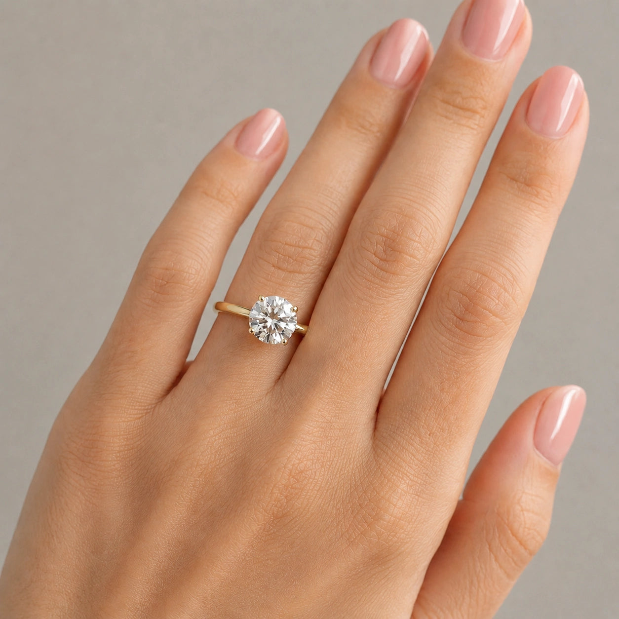 14K gold filled moissanite solitaire engagement ring set in 4-prong worn on model hand resting on marble surface - Sensitive Stones