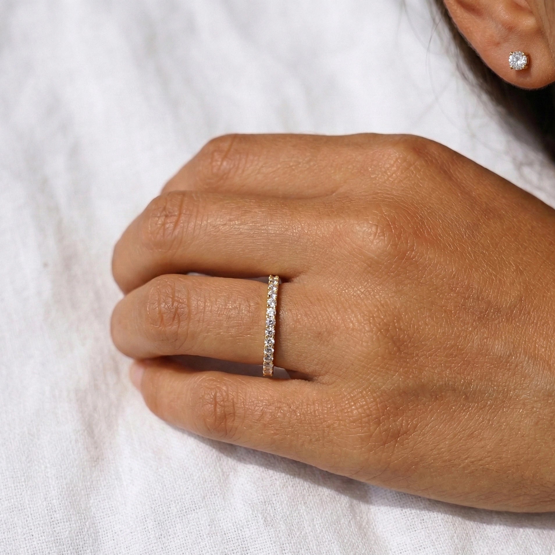 Soft portrait of a woman wearing a moissanite sterling silver full eternity band in 18k yellow gold plating - Sensitive Stones