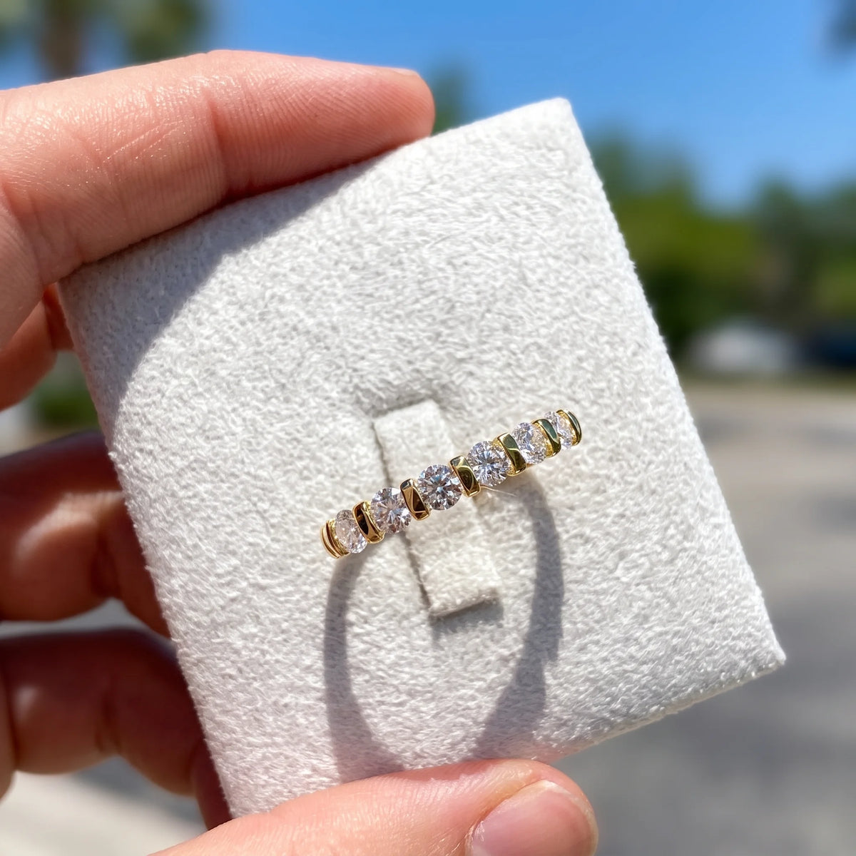 14K gold filled moissanite half eternity ring in yellow gold held in natural daylight showing stone sparkle - Sensitive Stones