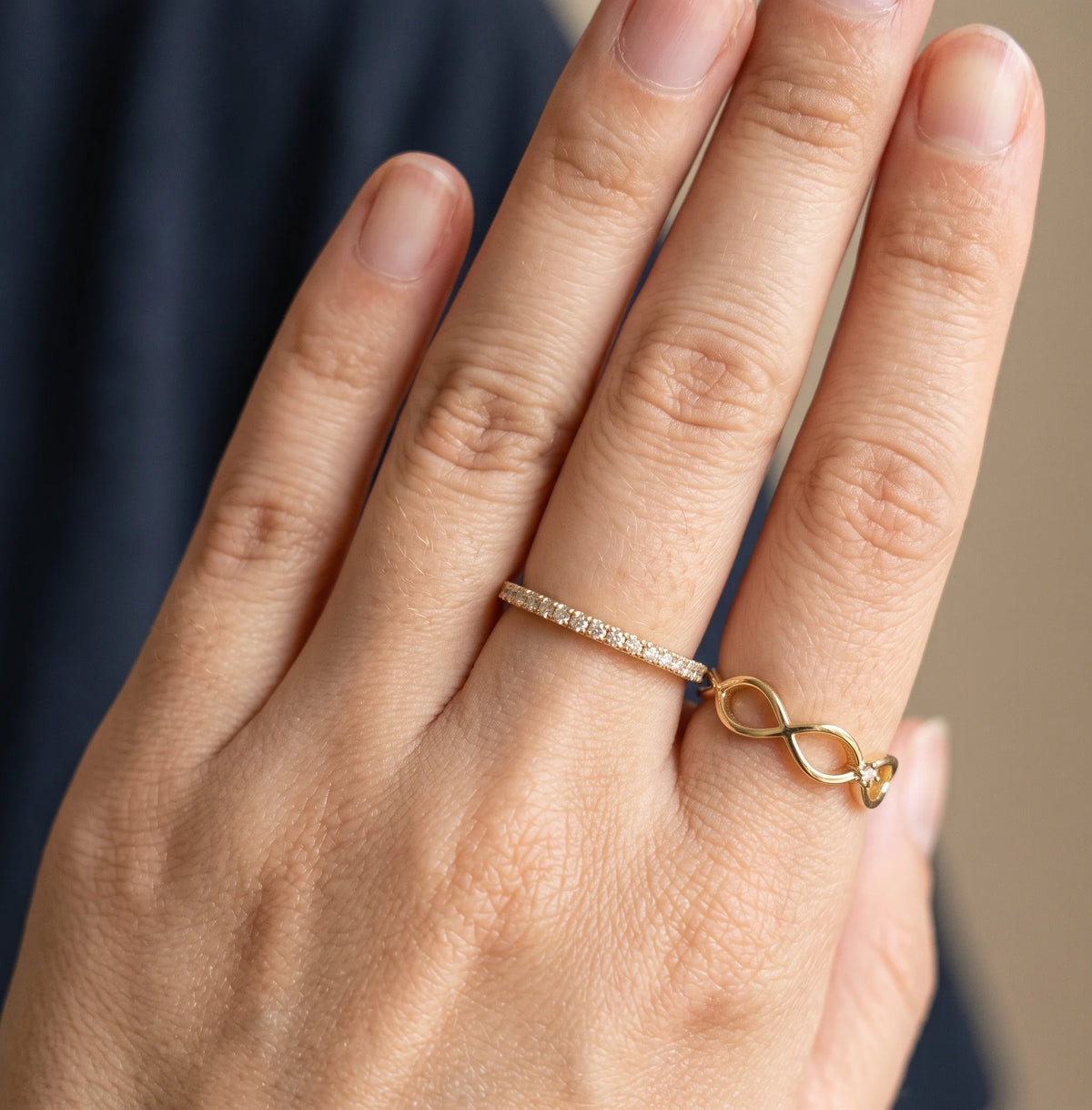 Hand wearing the moissanite half eternity ring in a yellow gold finish alongside a gold infinity ring sold separately - Sensitive Stones